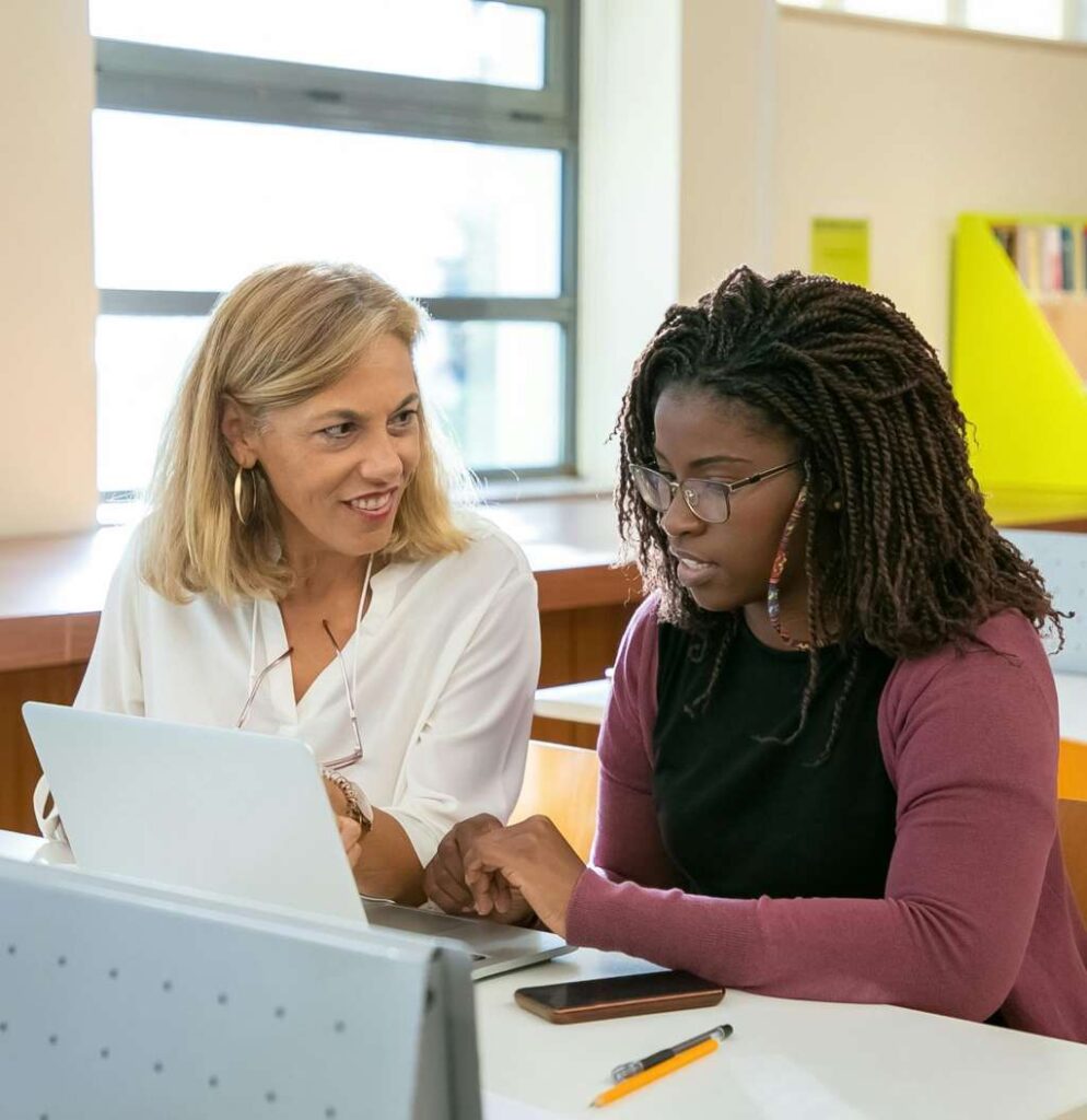 Student working one-on-one with a college essay coach, reviewing a personal statement on a laptop